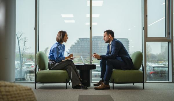 Two diverse professionals in a modern office engaged in conversation