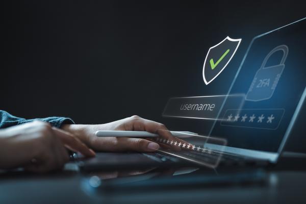 hands typing on open laptop with shield icon with green tick