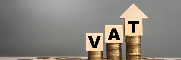 Image of three wooden blocks each on a stack of coins with the letters V A T on each of the blocks