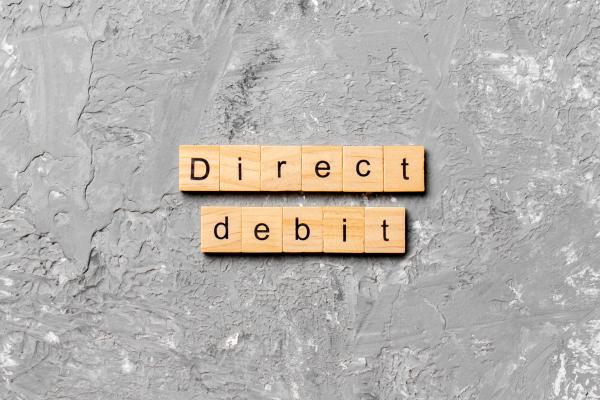 Wooden blocks spelling out "direct debit" on a grey background