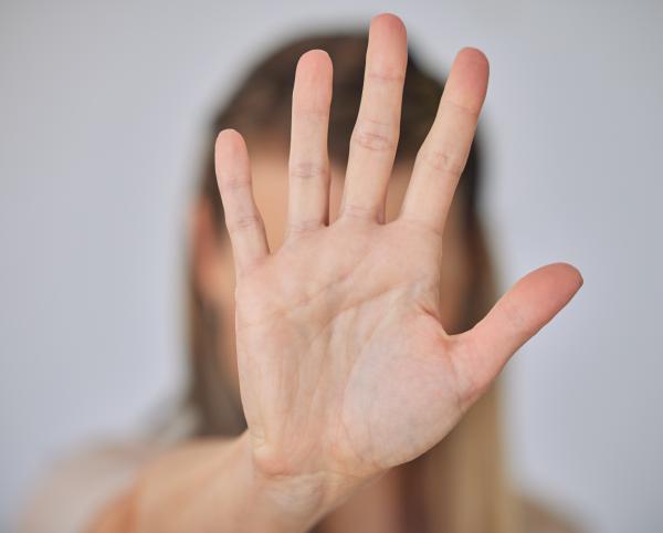 Woman's hand held up, palm to the camera with fingers outstretched, blocking her face
