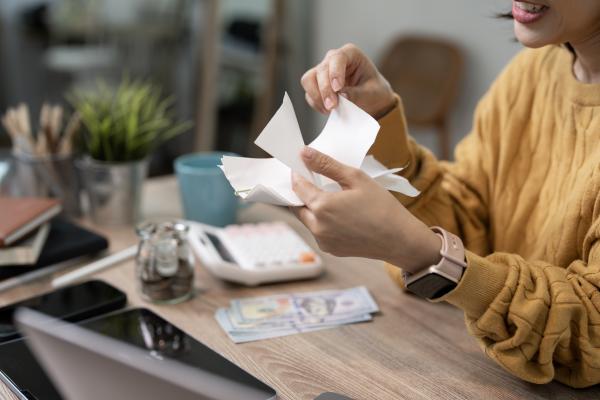 Woman sat at desk holding paperwork - calculator and bank notes on the desk