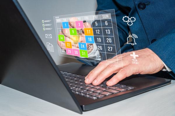 Man using laptop, virtual graphics of a calendar appear above the keyboard with icons for checklists, reminders, emails and new events